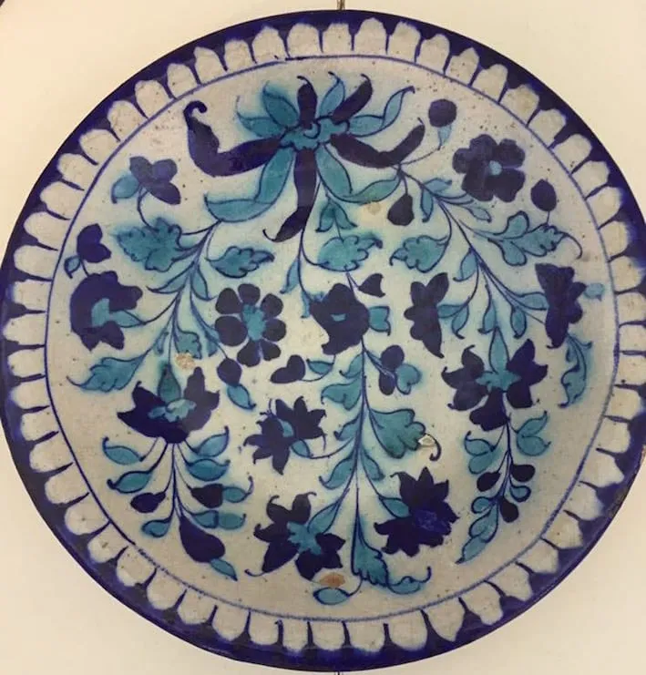 Glazed terracotta plate on circular foot, decorated by a floral pattern in cobalt blue and turquoise