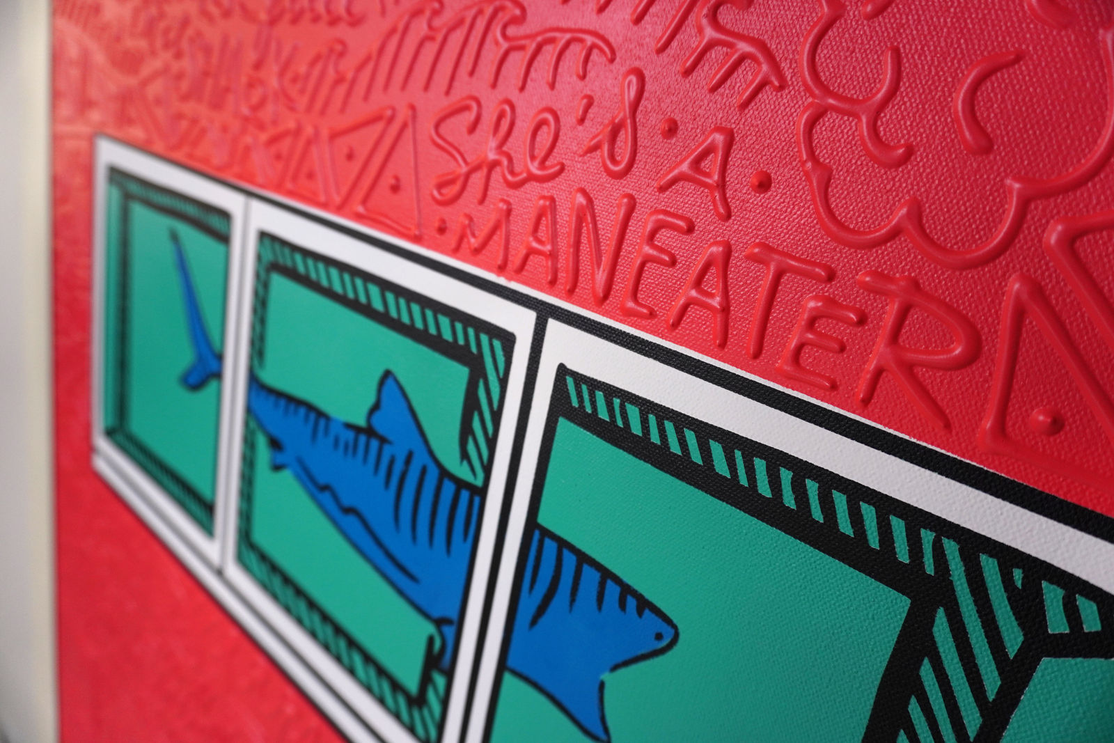 Detail photo of “El Tiburón”, painting by Cayla Birk artist from South Florida. Available at Carousel Fine Art Chicago. The artist’s technique blends traditional acrylic paints with unique materials, creating a distinct mixed media style. Birk's work is marked by intricate designs and recognizable gestures, combining contemporary culture, history, music, and literature. Her art challenges conventional thinking, offering new and unexpected experiences. Colors of this work : Red, Blue, Teal, Beige, White, Black