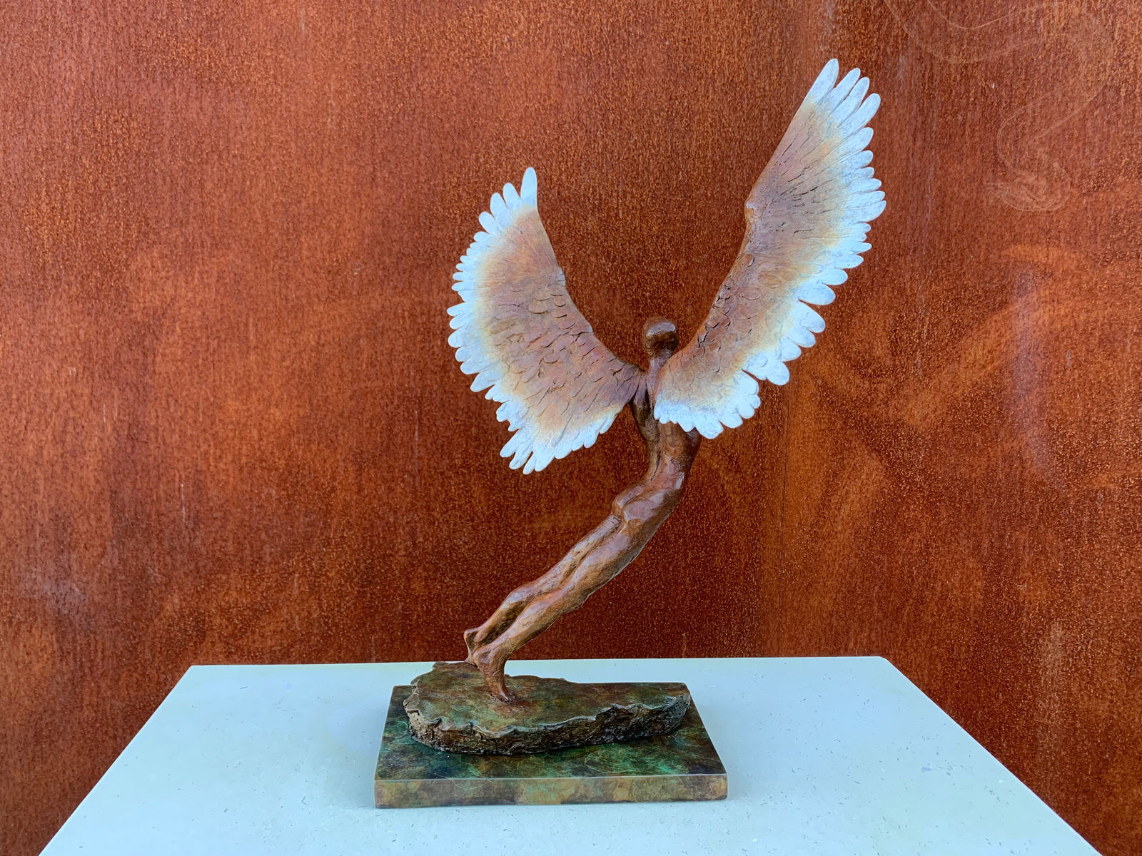 Figurative bronze sculpture of mythical Greek winged figure Icarus by Nicola Godden, displayed on plinth.