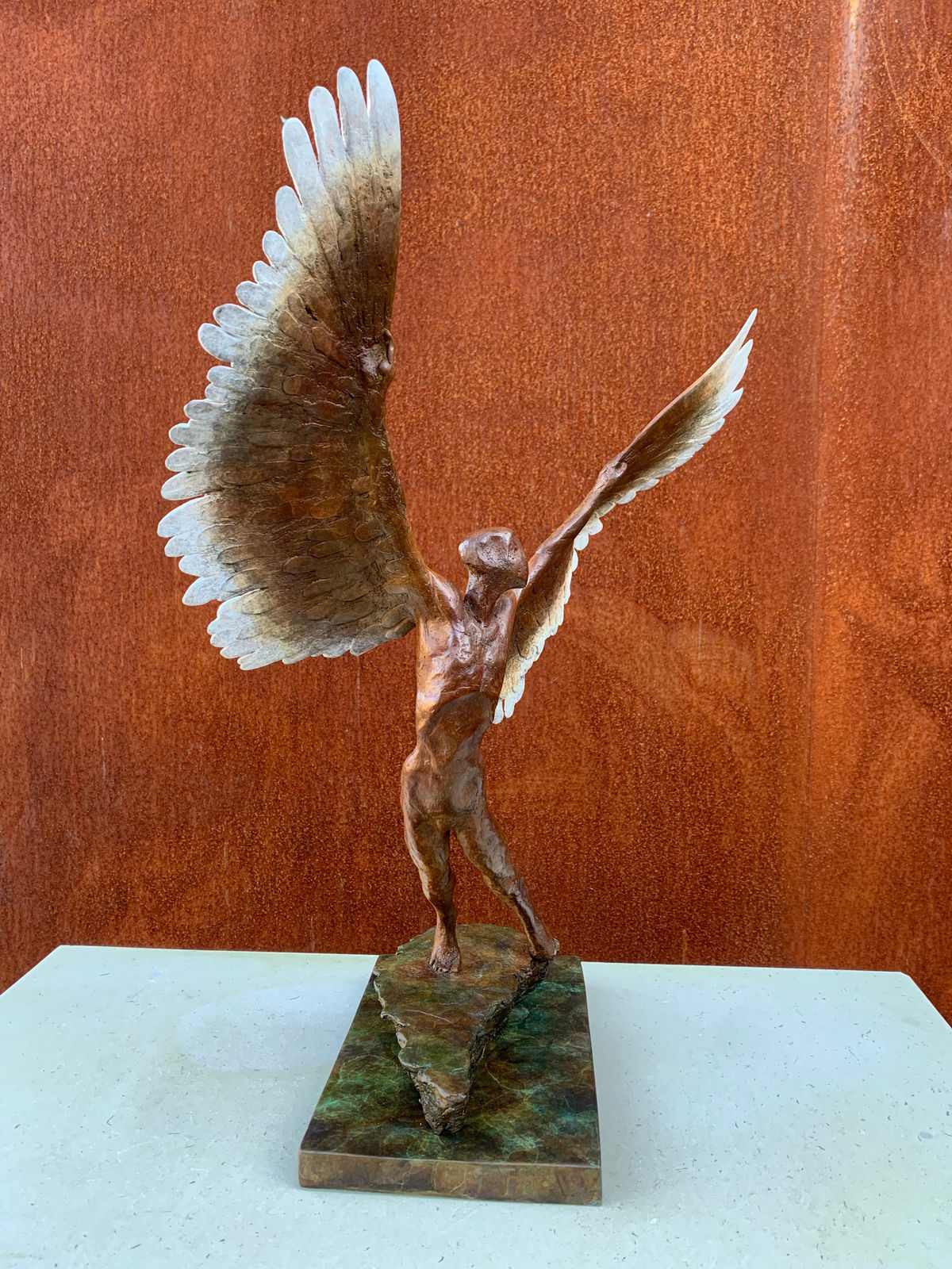 Figurative bronze sculpture of mythical Greek winged figure Icarus by Nicola Godden, displayed on plinth.