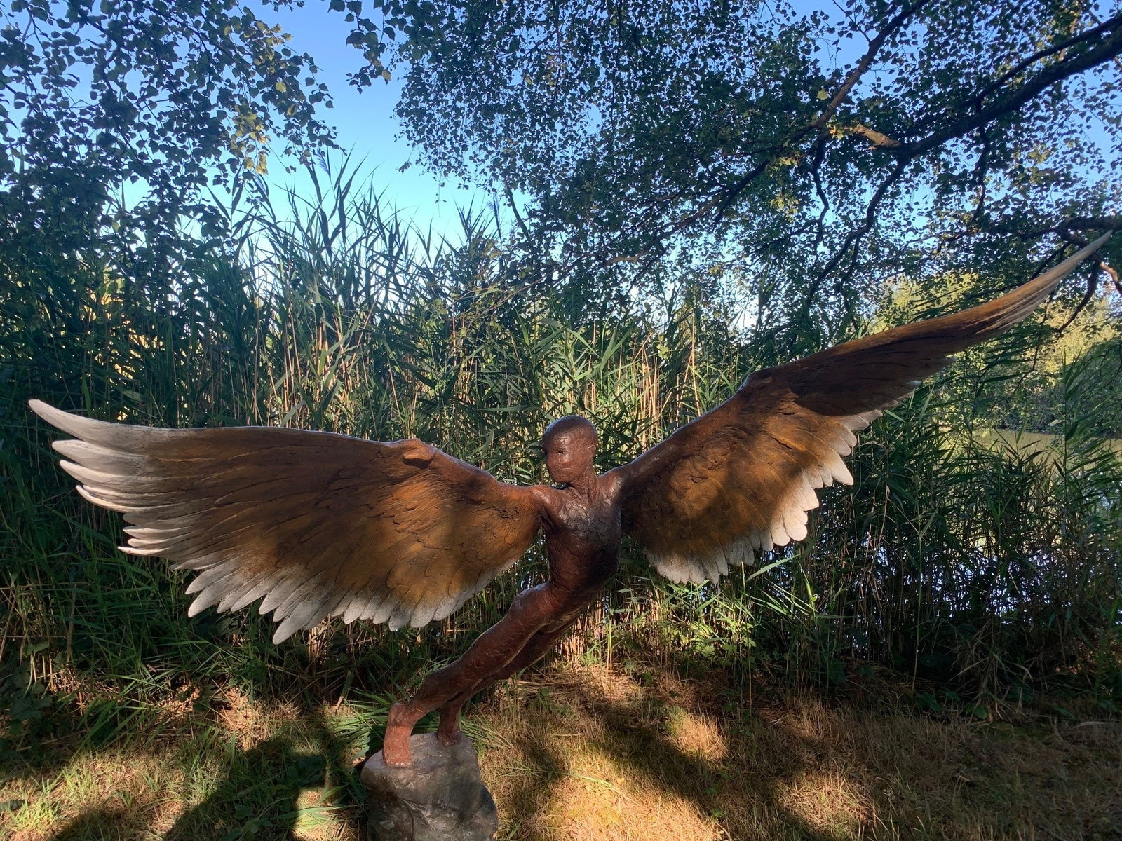 Bronze resin sculpture of mythical Greek winged figure Icarus by Nicola Godden, displayed on integral stone plinth