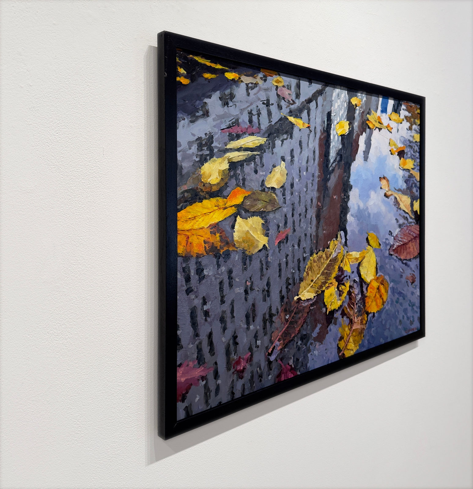 Reflection of city buildings in a puddle with fall leaves in it