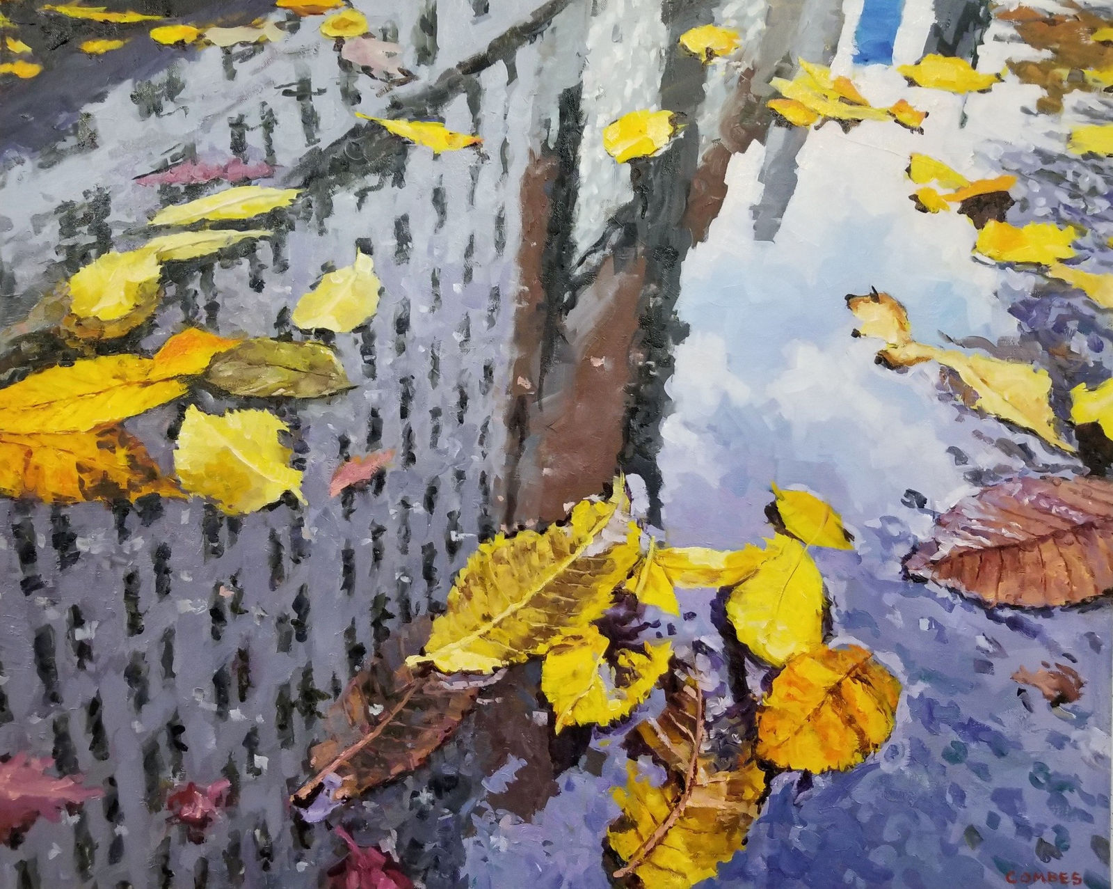 Reflection of city buildings in a puddle with fall leaves in it