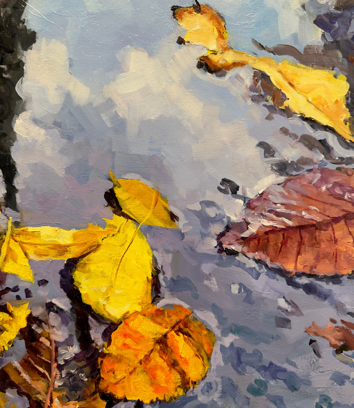 Reflection of city buildings in a puddle with fall leaves in it