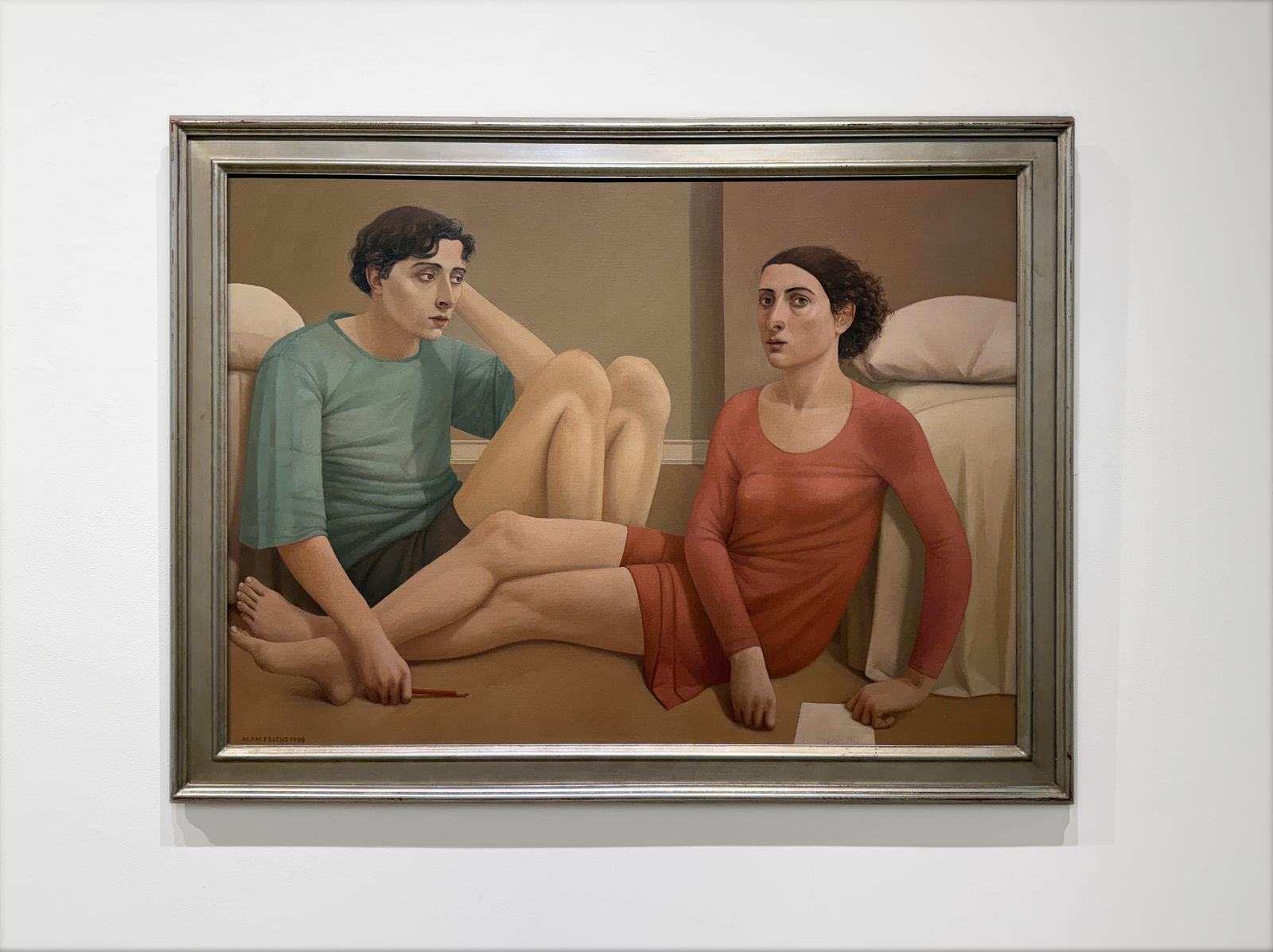 Man in a blue shirt and a woman in a red dress sitting on a bedroom floor