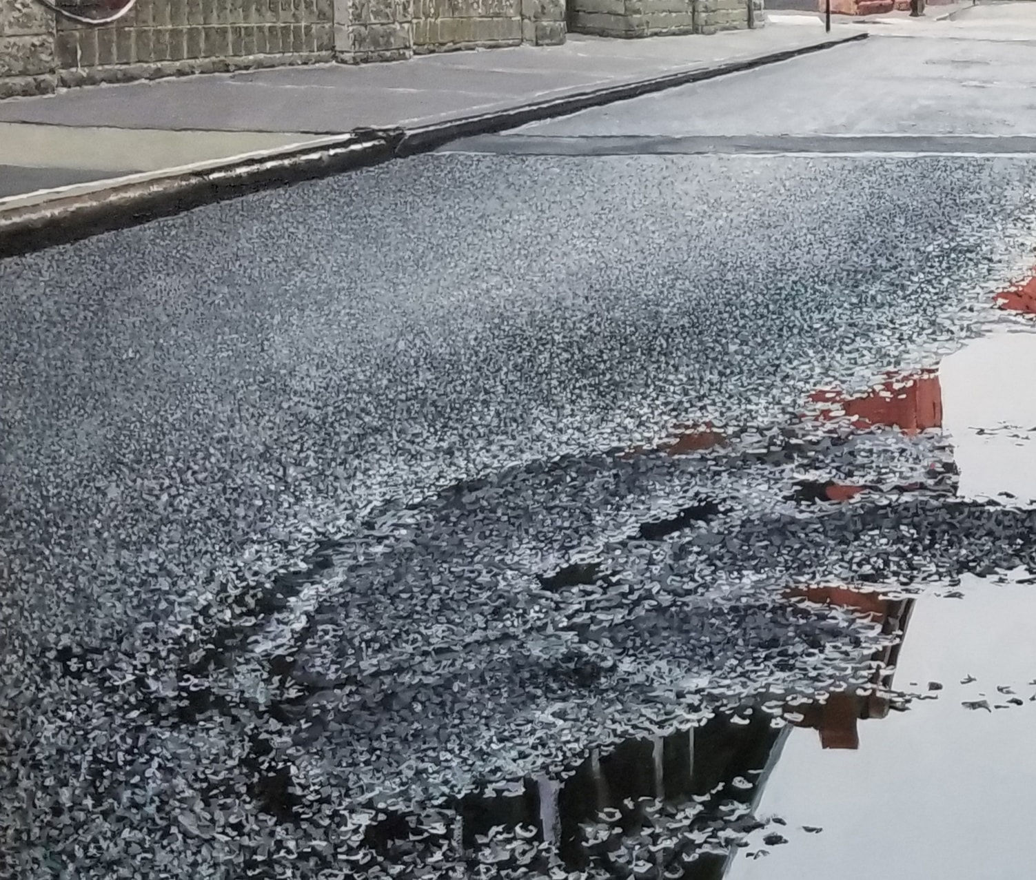 View from ground of puddle on Collister street reflecting grey sky