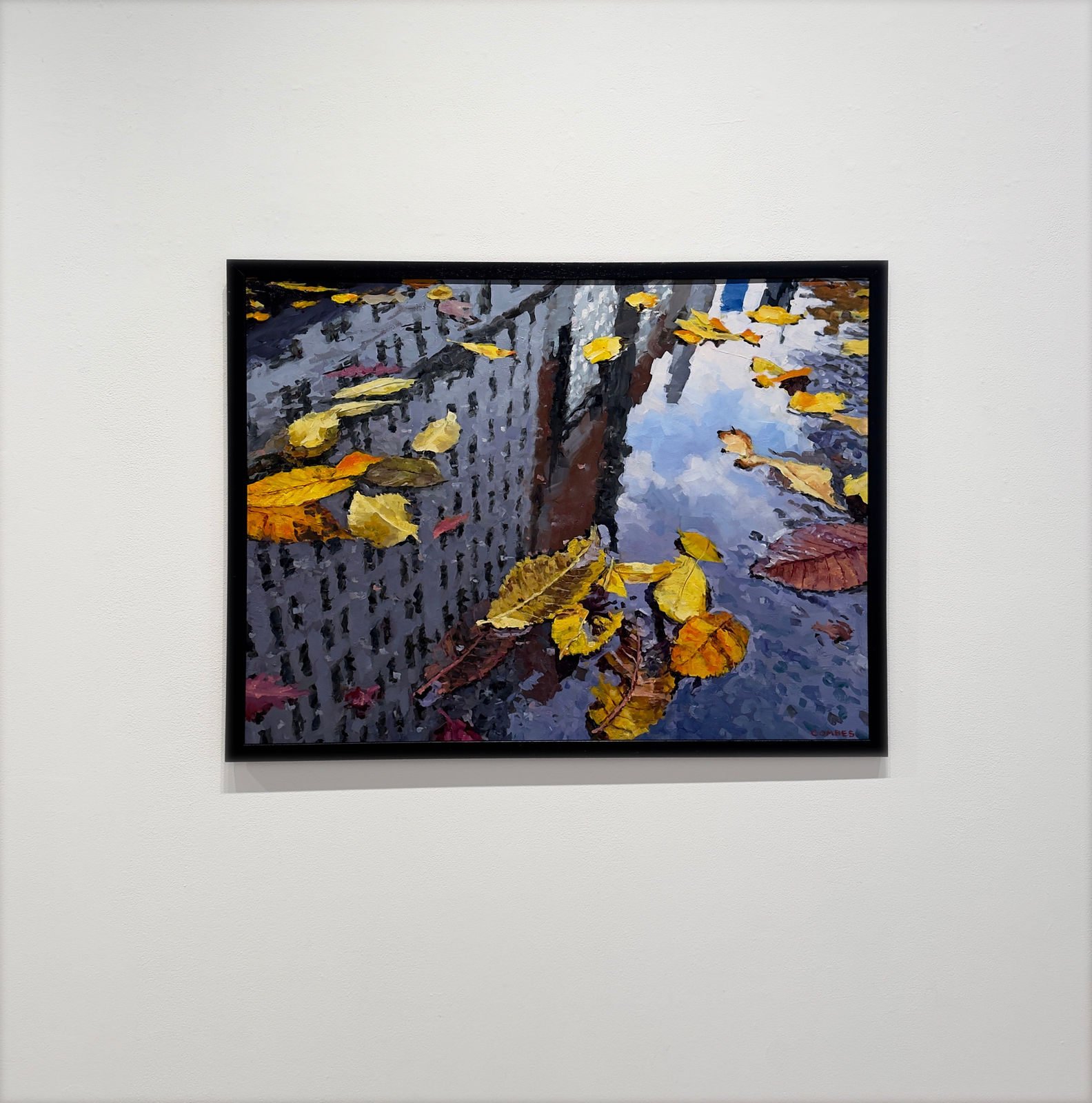 Reflection of city buildings in a puddle with fall leaves in it