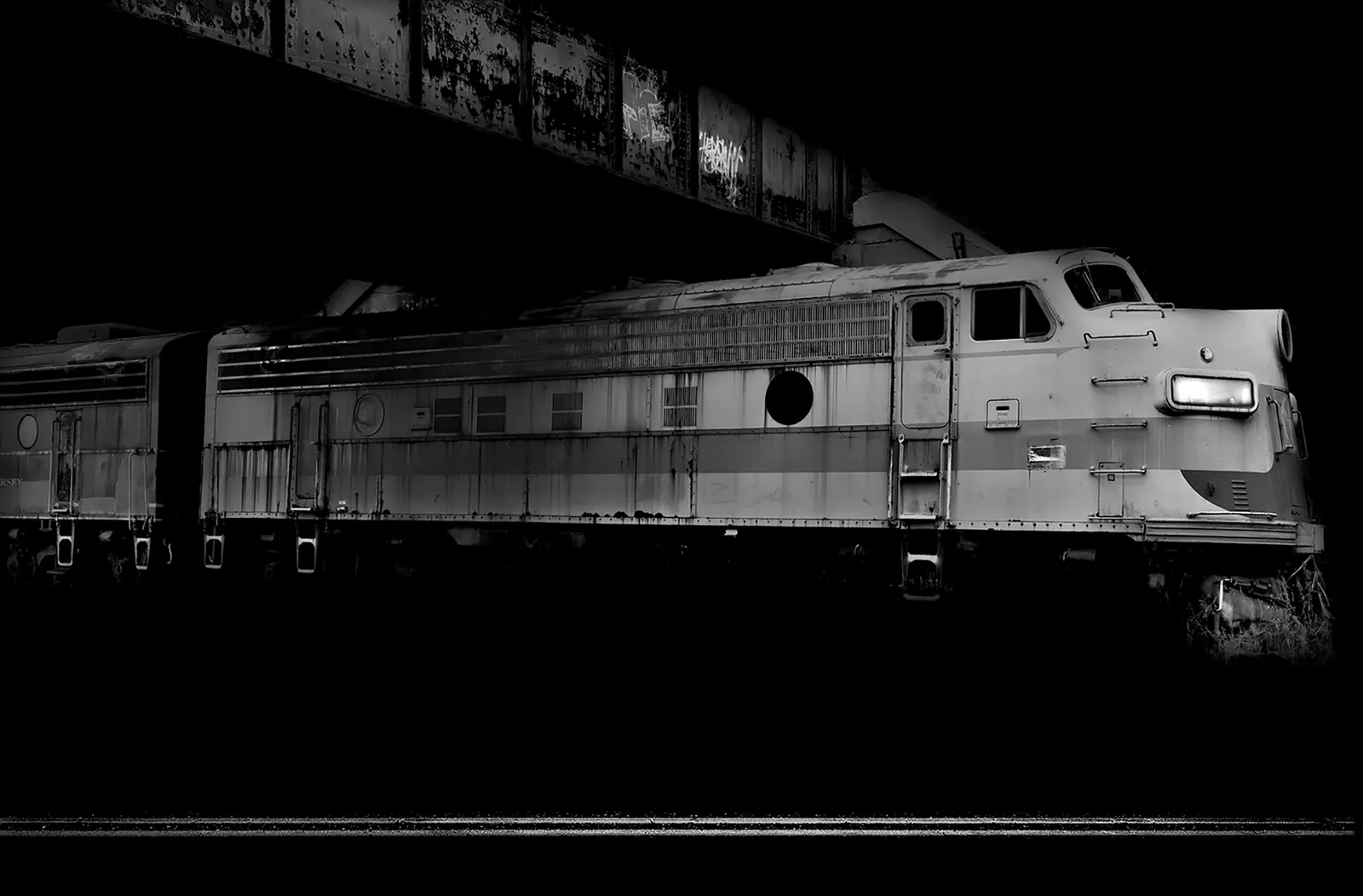 train going under bridge photo at night by Michael massaia
