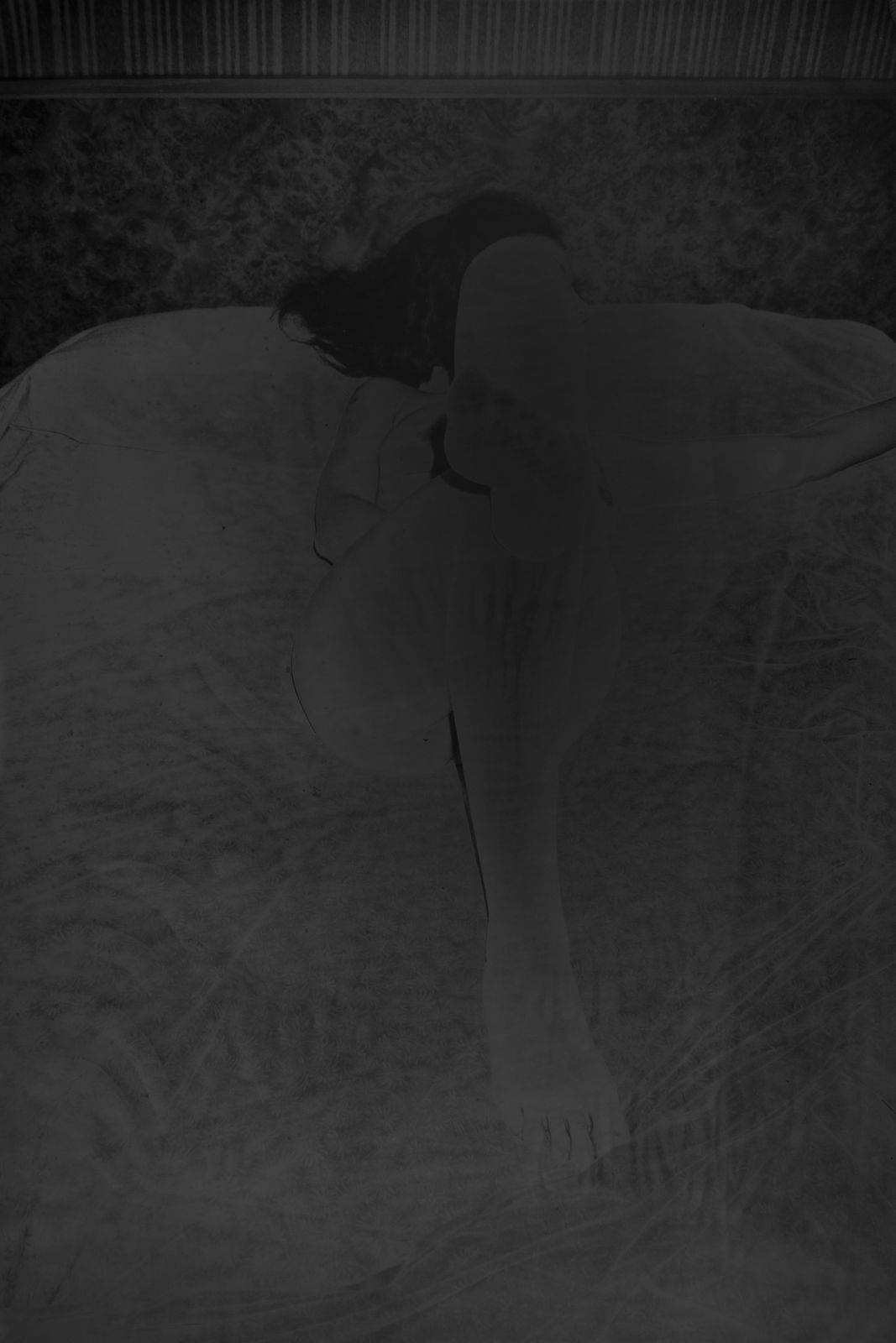 An inkjet print of a shadowy figure on a bed.