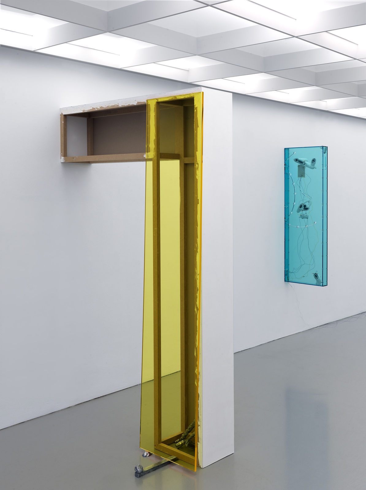 a post-and-beam-like structure coming out of a white wall to form an arch, colored with yellow plexiglass on one side.