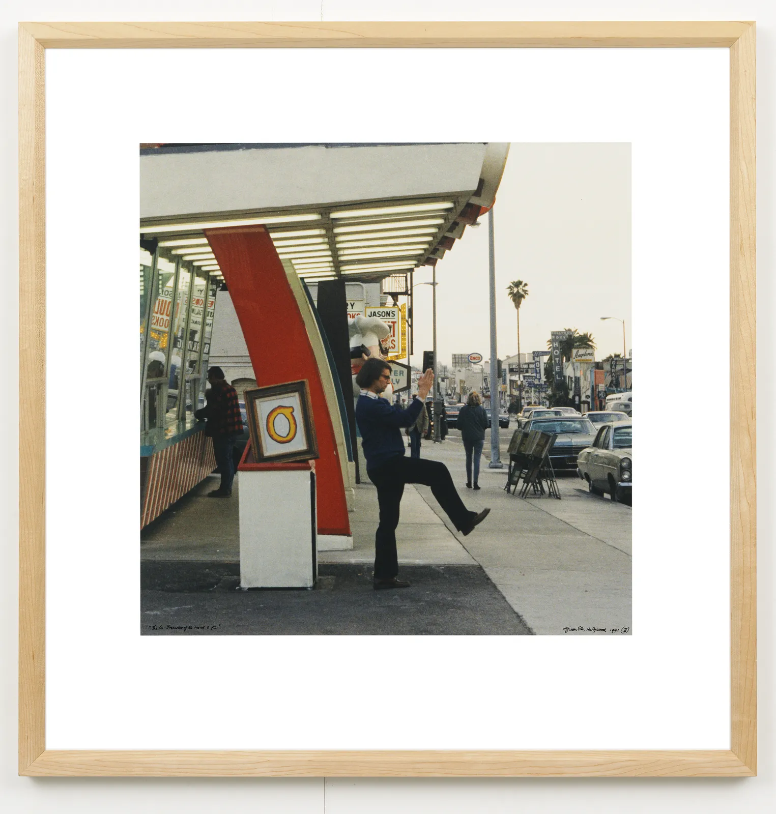 A framed image of a man kicking his leg up next to a parking lot.
