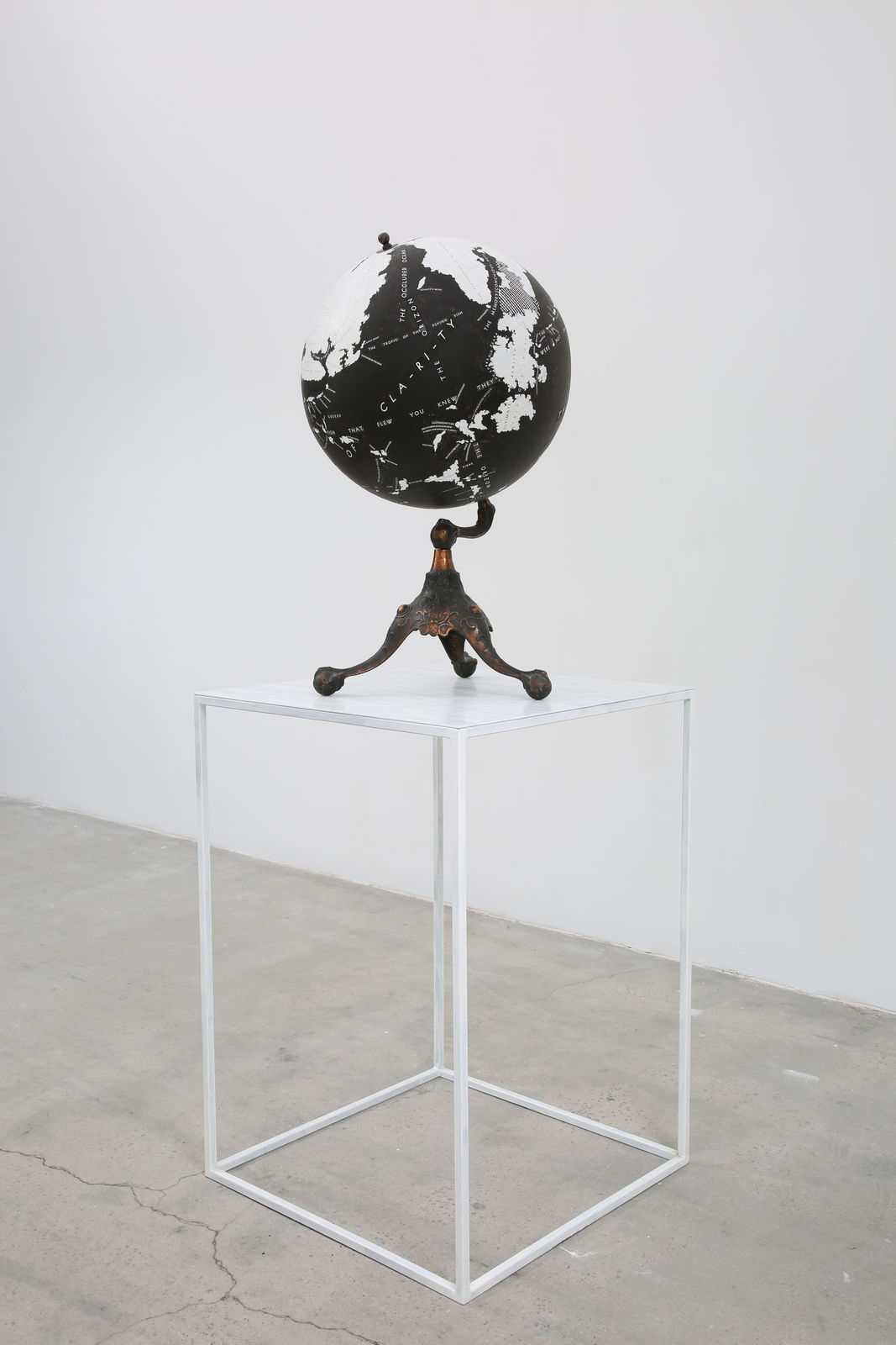 A black and white globe sits atop a white table.