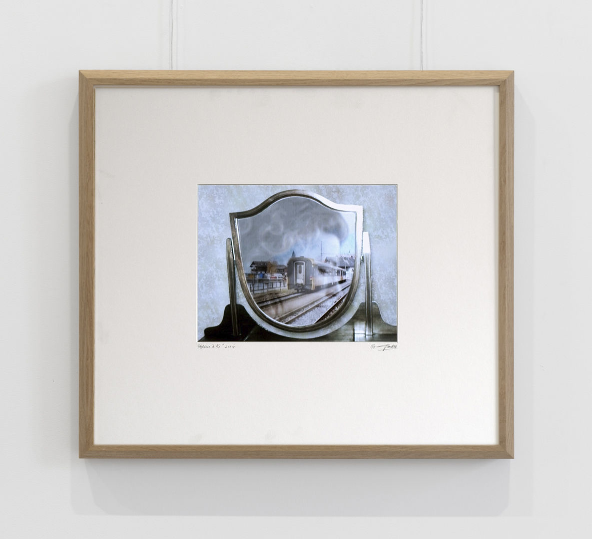 A framed photo of a mirror which contains a reflection of a train.