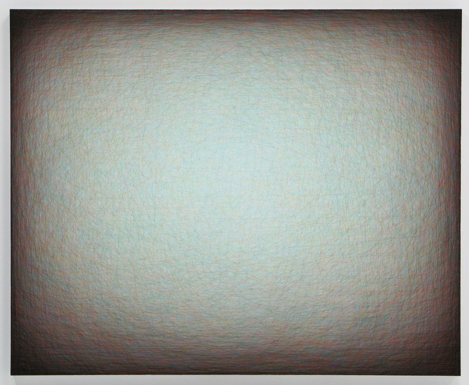 Layers of multi-colored threads strung across a rectangular wooden and plaster panel create the effect of a large glowing light blue center that is enclosed by a dark brown border