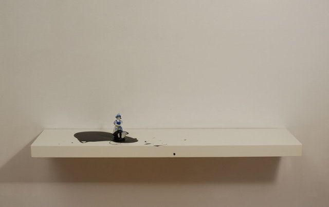 Digital photograph of an installation in which a white and blue porcelain figurine appears to be dancing on top a pool of black paint