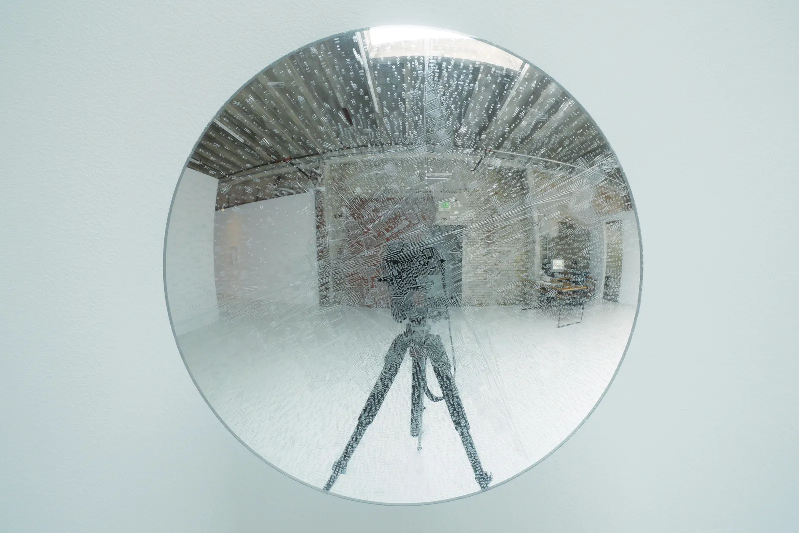 Front view of engravings on a clear disk, with reflection of tripod.