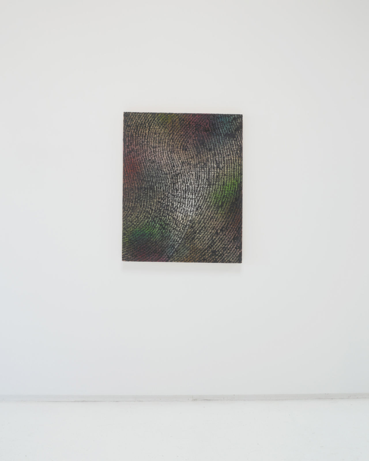 A multicolored abstract painting on canvas hanging on a white wall.
