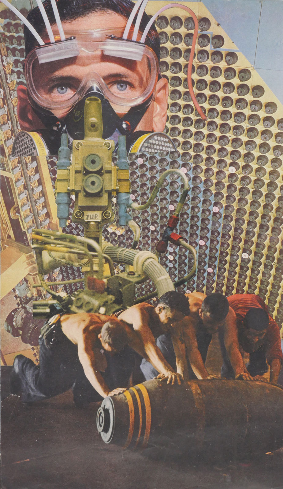 A man wears goggles and layers of circuit boards in the shape of a gas mask and looms above a group of men rolling a cylinder.