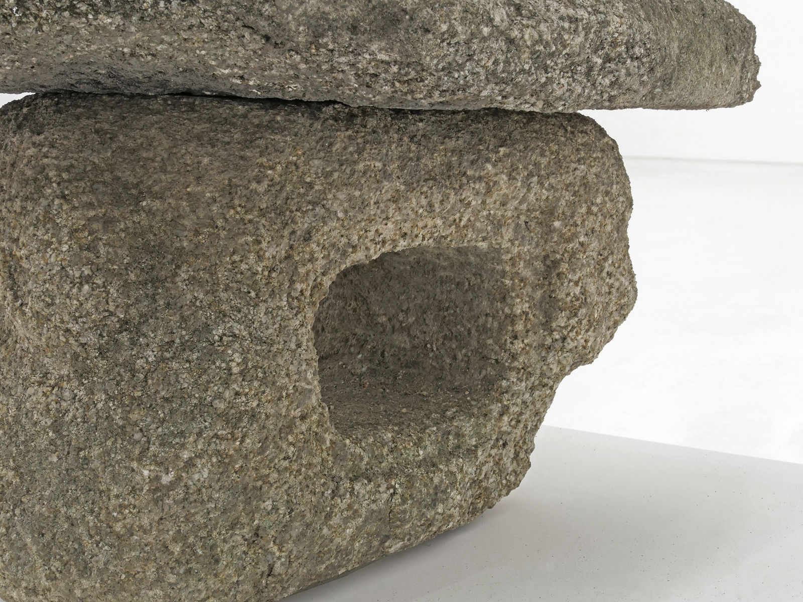 Detail of weathered stone sculpture with hole in the middle.