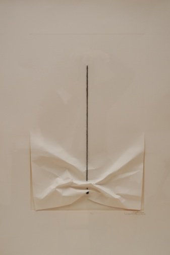 Piece of white wrinkled paper which appears to be further crinkled and pulled upwards by a straight line of black yarn