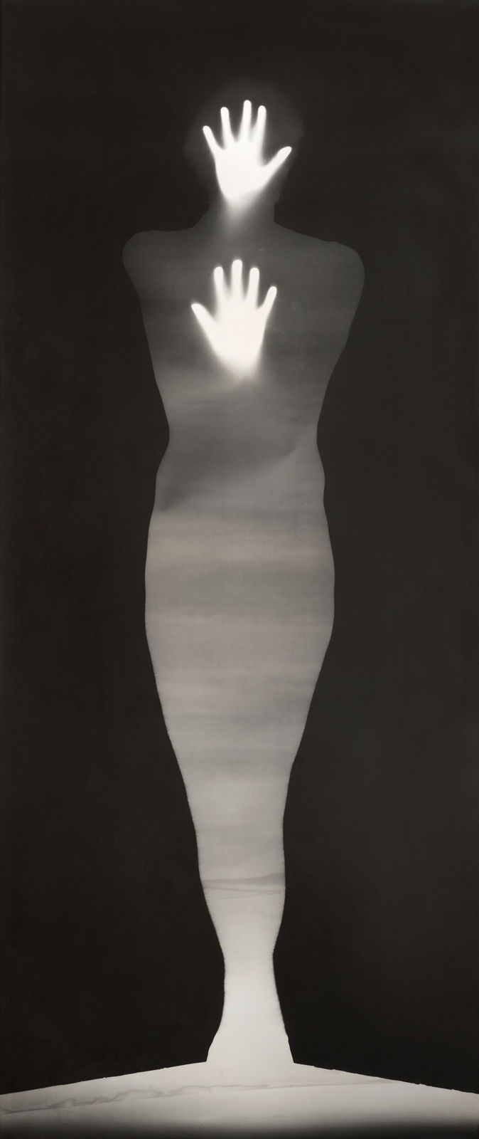 Black and white photograph whose edges have been blacked out to allow the remaining negative space to take the form of a body At the top of the piece two hands directly above and below each other appear to be glowing and pressing against the surface of the work from within