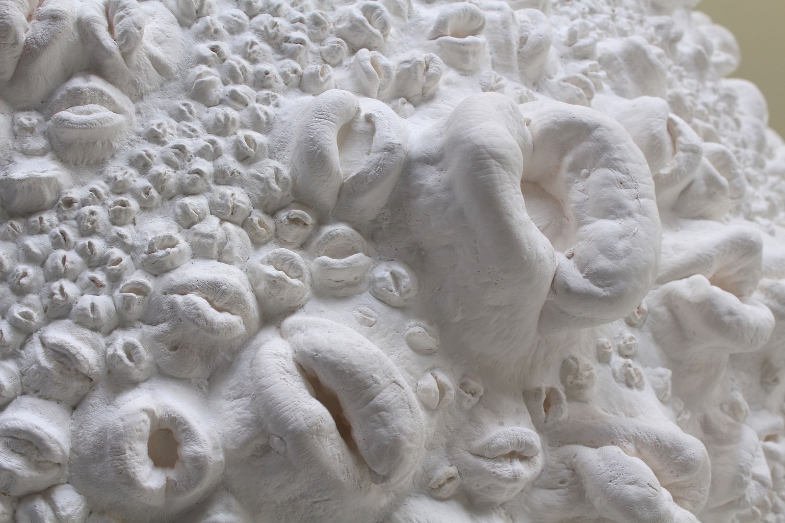 Detail of lips in varying sizes and expressions on moon's surface.