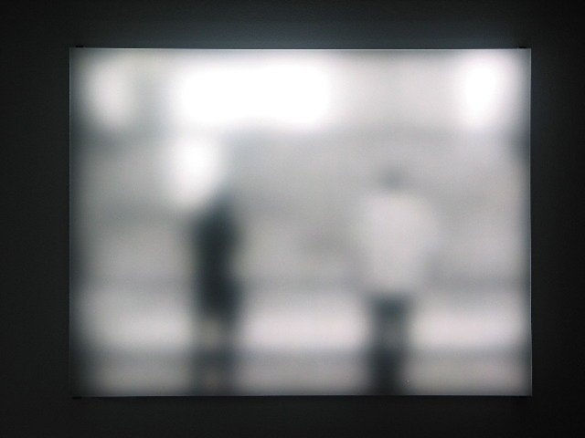 Still image of rectangular piece with white LEDs behind Plexiglass which display the scene of tourists at the World Trade Center Memorial in New York City