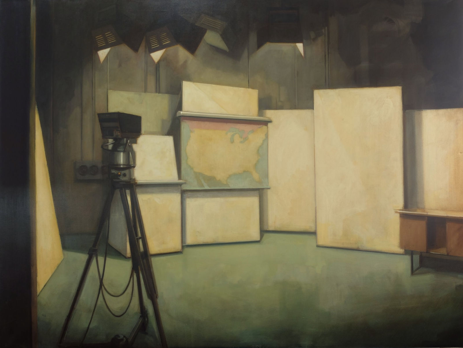 Several blank canvases stand on a stage beneath lights and in front of a video recorder. One of the canvas features a blank map of the United States and the edges of its neighbors Mexico to the south and Canada to the North.