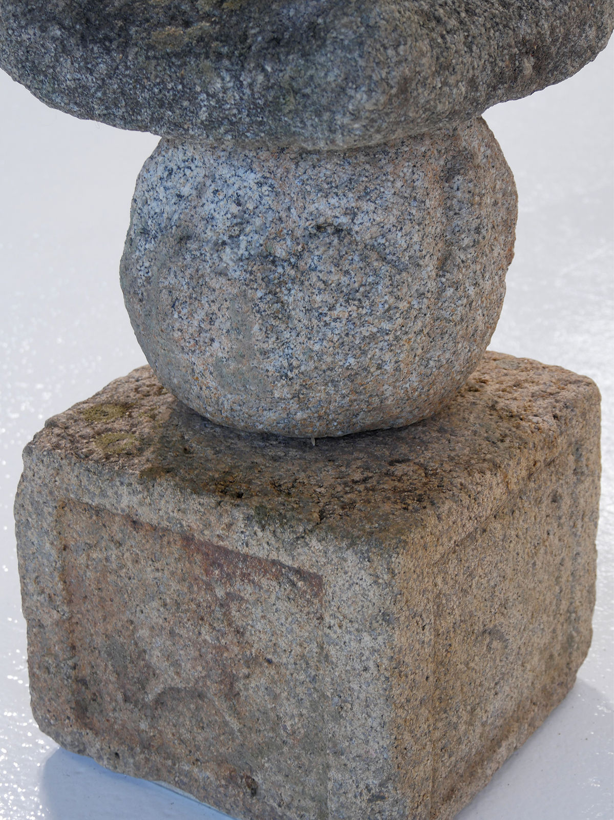 Square base and rounded body of stone sculpture.