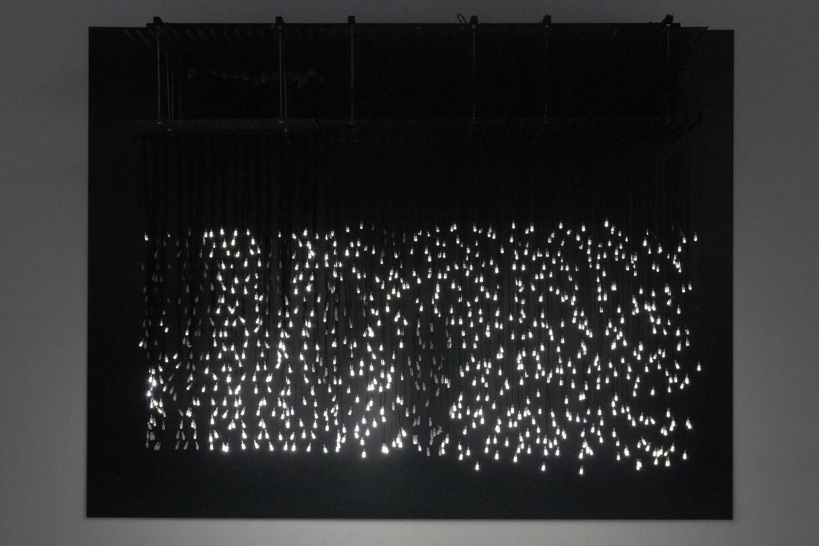 An image of piece with scattered string lights showing people walking.