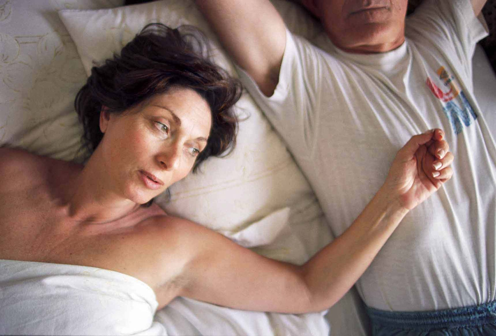 Elinor Carucci My Parents #1 portrait of artist's parents in bed mother under covers with arm on father's torso