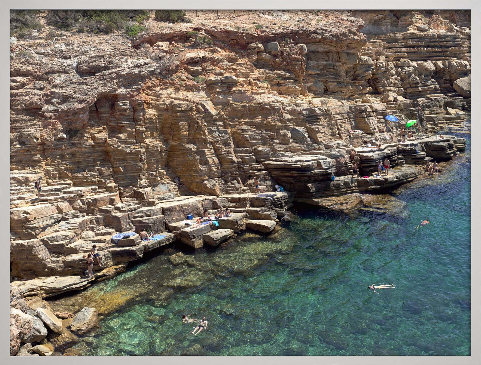 Beachgoers floating in blue water at Cala Llosa South, Ibiza, by Massimo Vitali