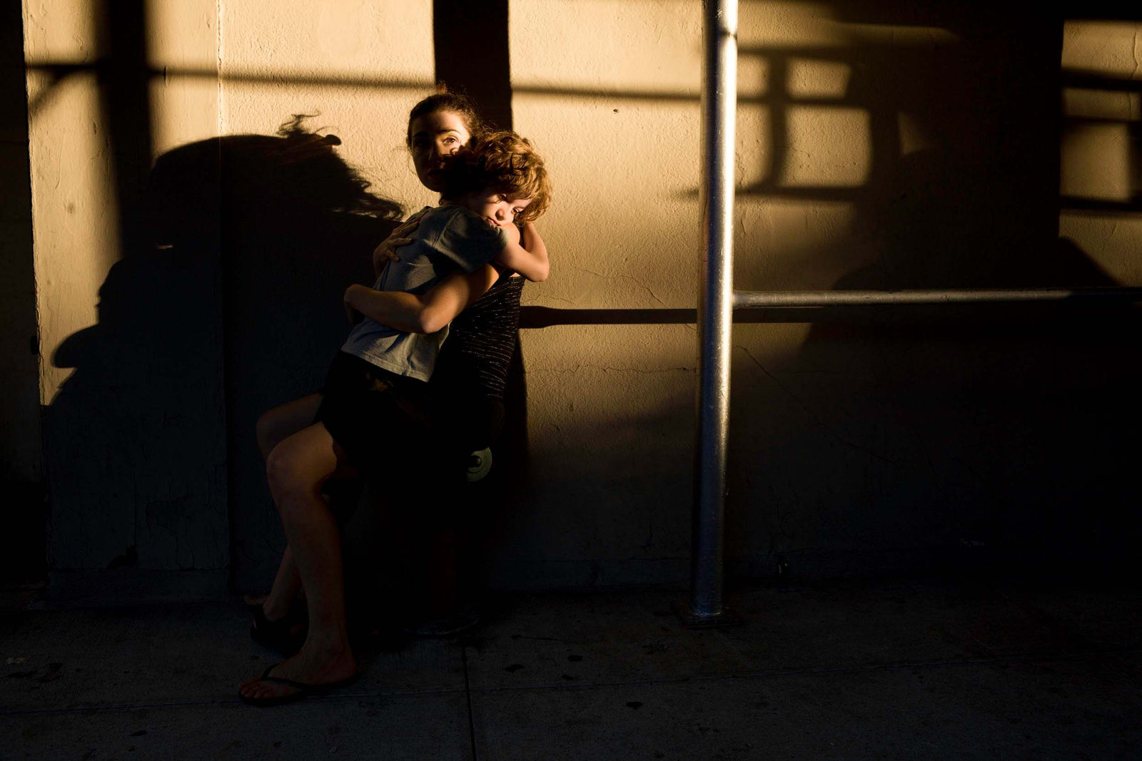 Elinor Carucci photograph of the artist holding her child on the sidewalk in front of a building