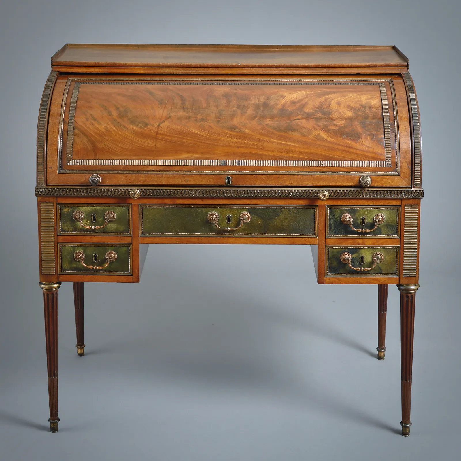 GEORGE III GILT-COPPER MOUNTED MAHOGANY AND MOROCCO LEATHER CYLINDER BUREAU