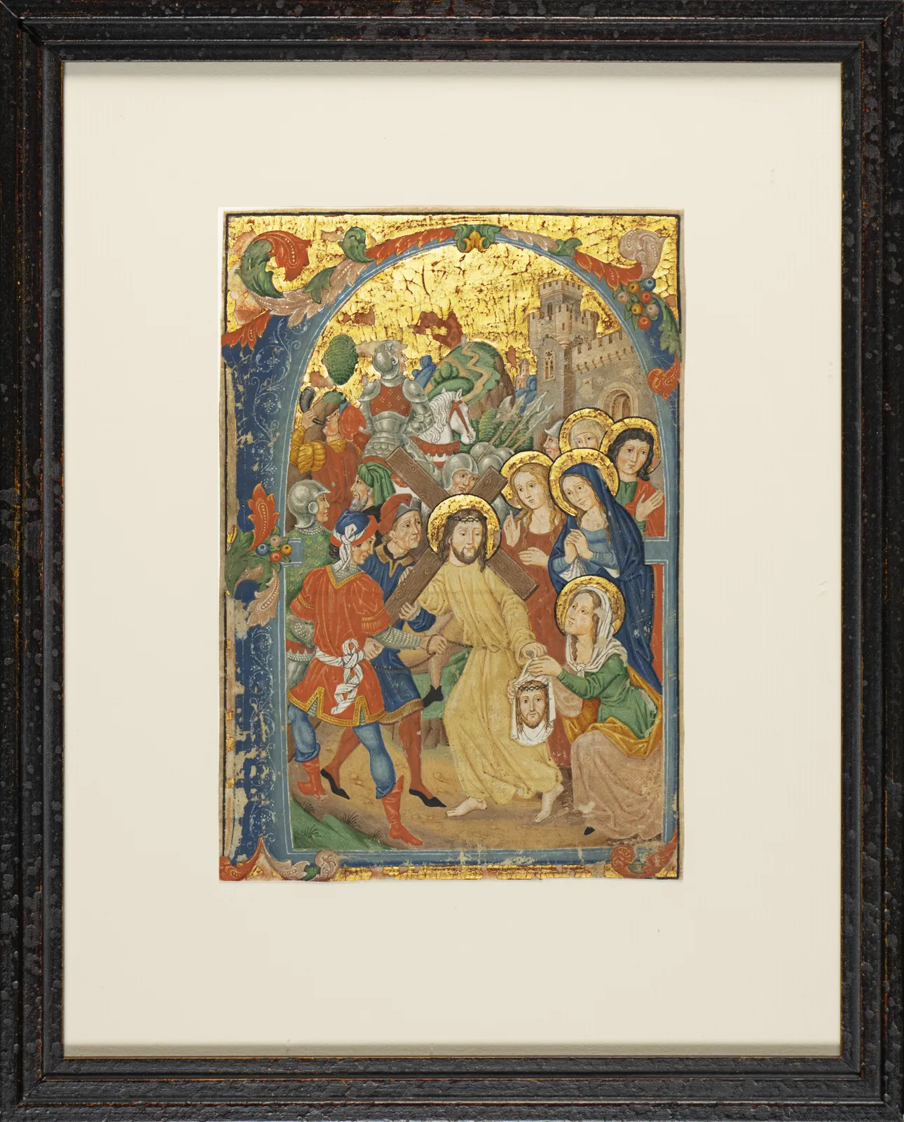 Framed hand-painted manuscript illumination of the Ascent to Calvary by the Spanish Forger, showing Jesus carrying the cross and Saint Veronica, framed by a blue and gold Gothic border.