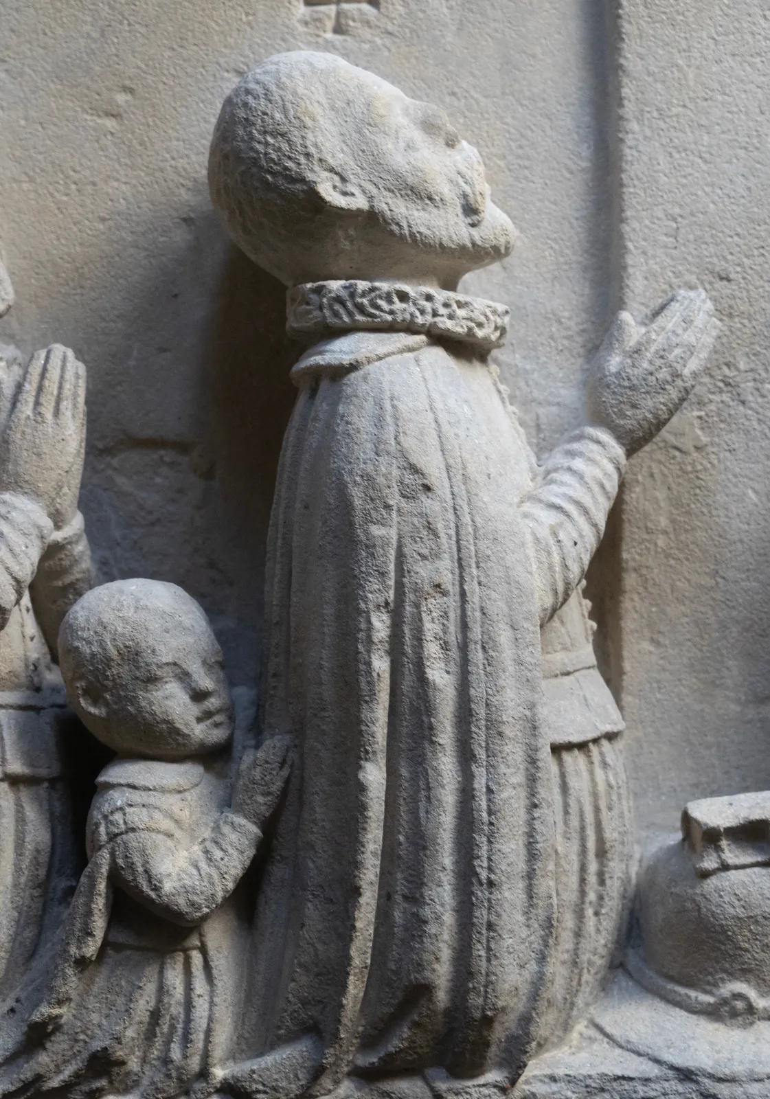 Detail of a fragment of an epitaph from c. 1600, depicting a family in prayer. On the left, two bearded men and a small child kneel, facing right with their hands clasped. On the right, four women kneel, facing left in a similar prayerful pose. All figures are dressed in period clothing with prominent ruffled collars. La Gabrielle Fine Arts SA, Geneva.