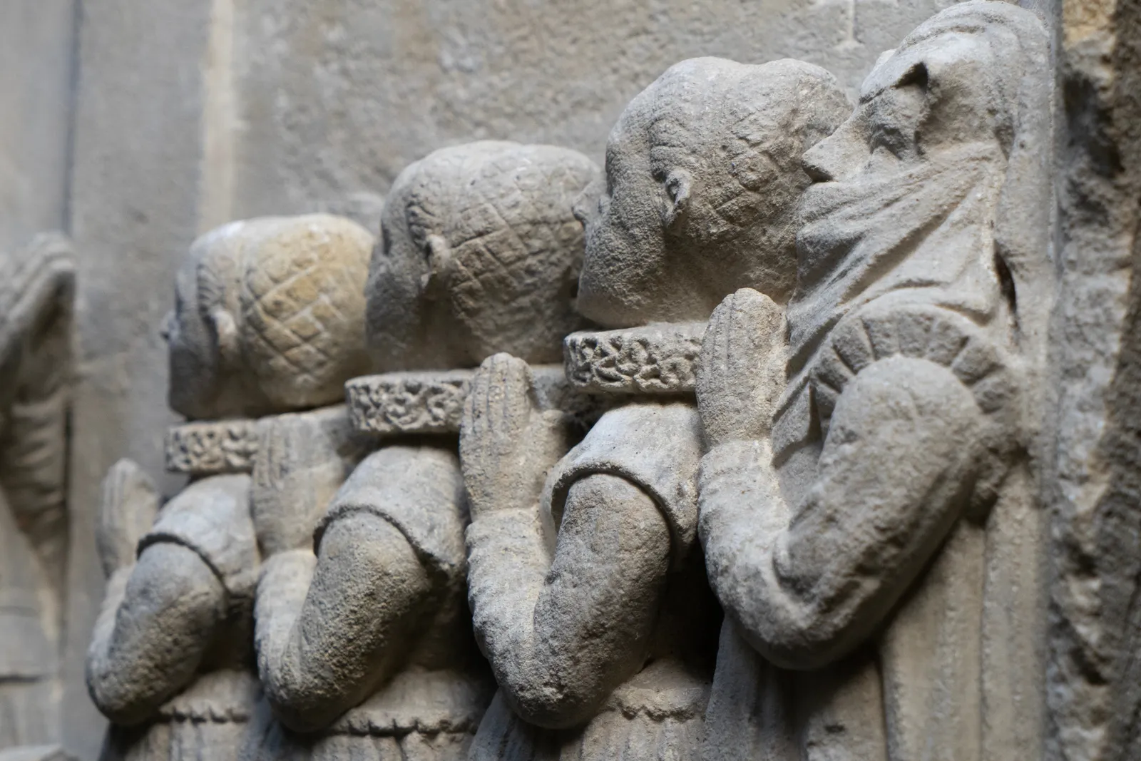 Detail of a fragment of an epitaph from c. 1600, depicting a family in prayer. On the left, two bearded men and a small child kneel, facing right with their hands clasped. On the right, four women kneel, facing left in a similar prayerful pose. All figures are dressed in period clothing with prominent ruffled collars. La Gabrielle Fine Arts SA, Geneva.
