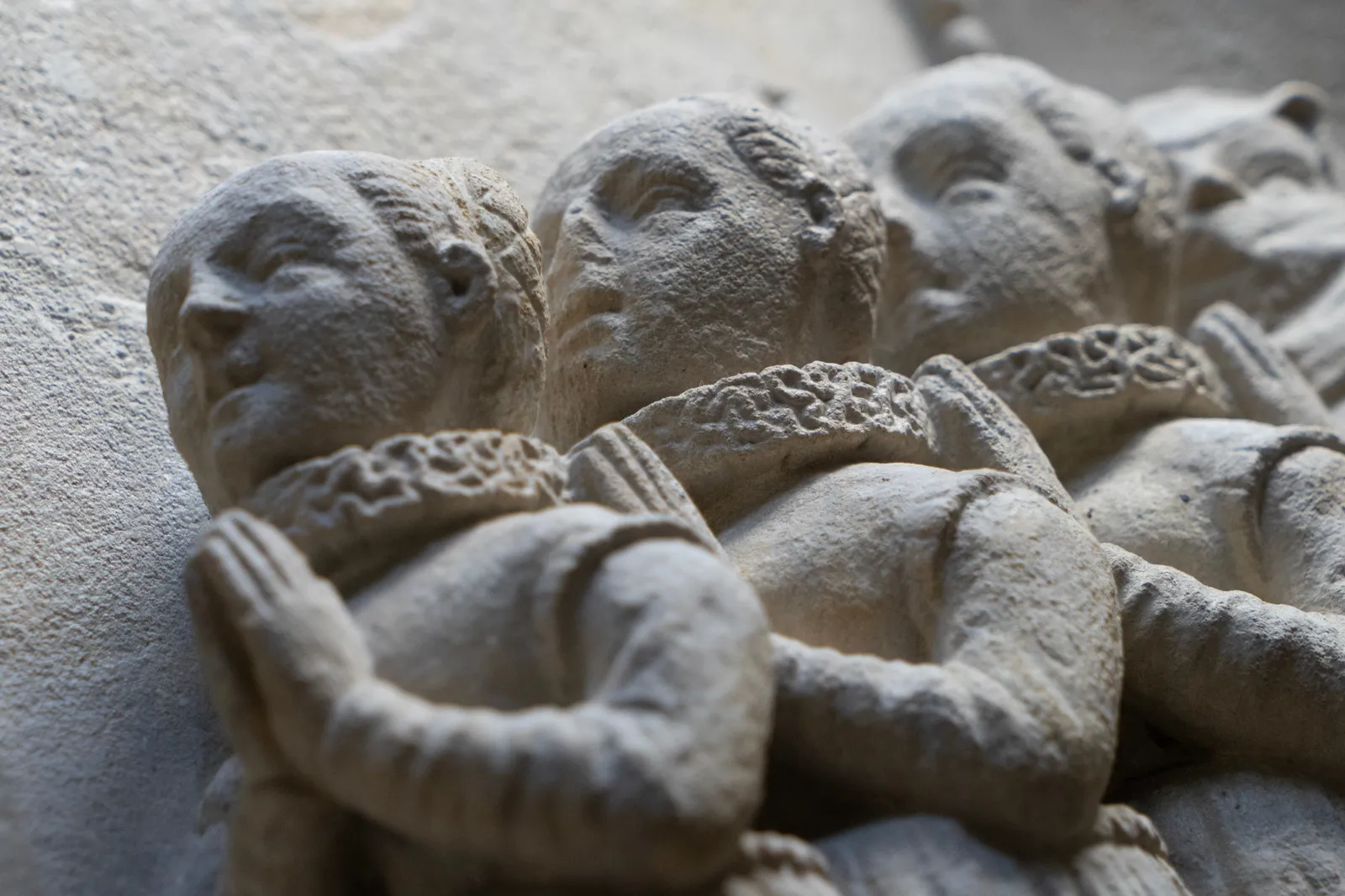 Detail of a fragment of an epitaph from c. 1600, depicting a family in prayer. On the left, two bearded men and a small child kneel, facing right with their hands clasped. On the right, four women kneel, facing left in a similar prayerful pose. All figures are dressed in period clothing with prominent ruffled collars. La Gabrielle Fine Arts SA, Geneva.
