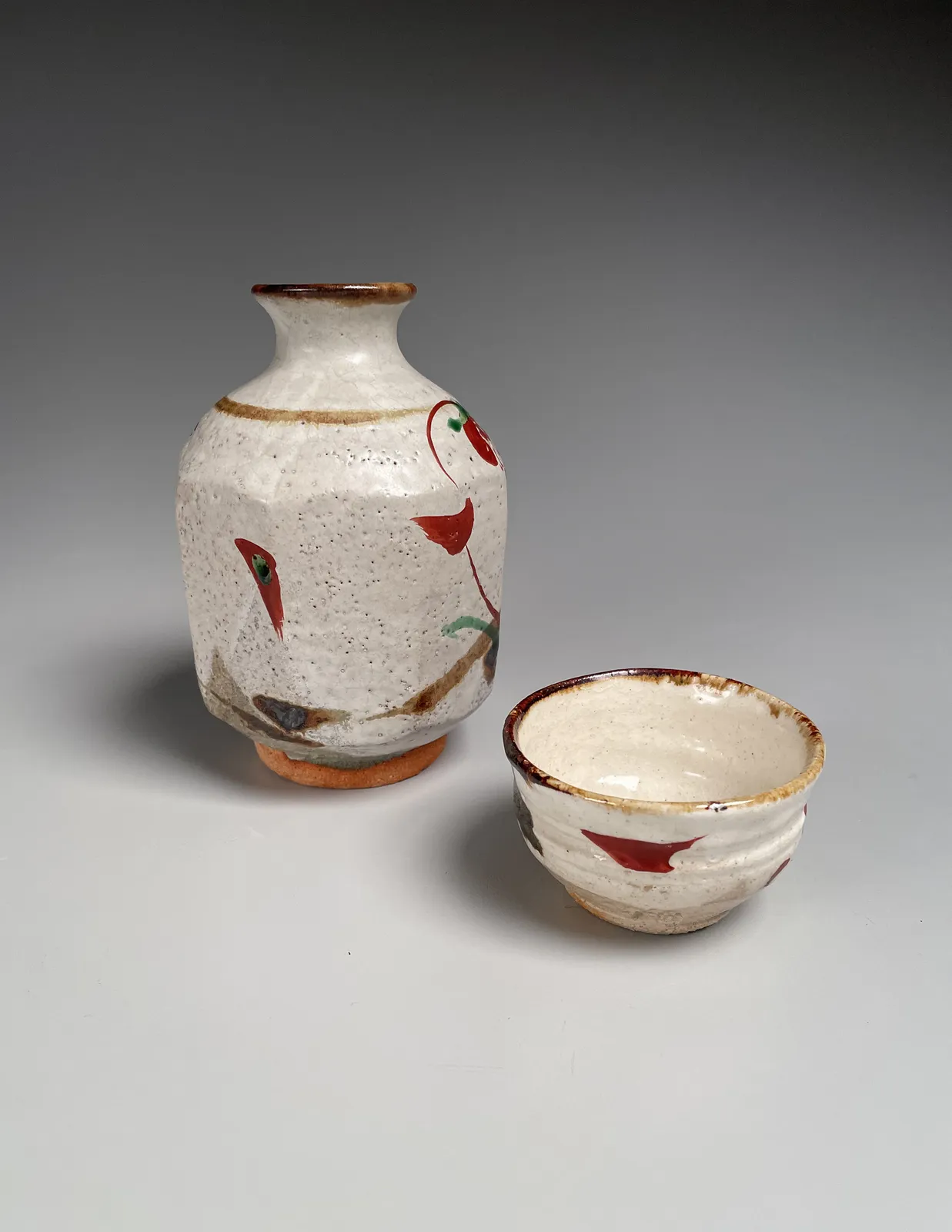 FUJIMOTO YOSHIMICHI (NŌDŌ), Stoneware tokkuri (sake flask) and guinomi (sake cup) with red and green floral patterning, ca. 1975