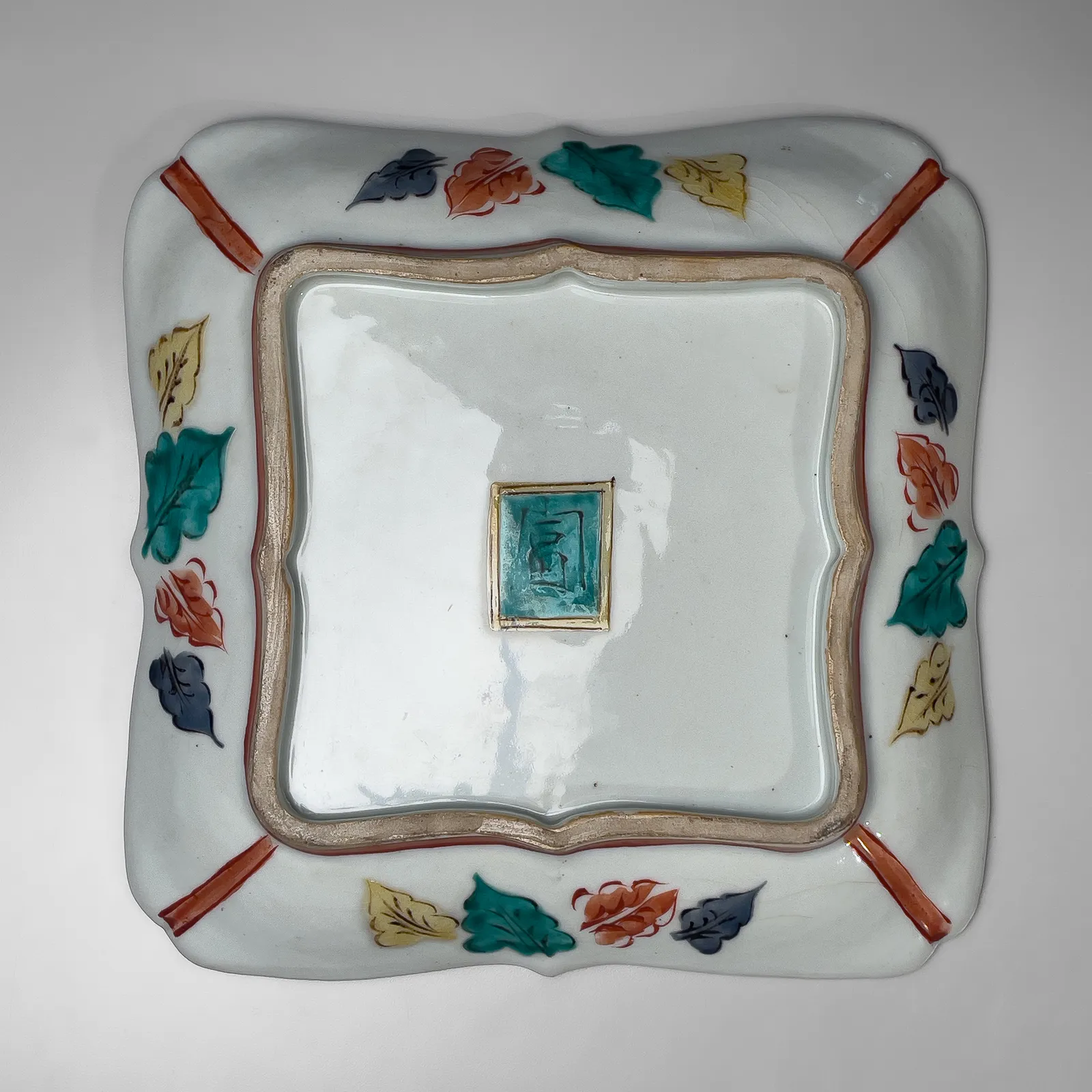 TOMIMOTO KENKICHI, Iro-e (enamel overglaze) slightly recessed rounded square platter with foliated rim, sarasatic-patterned four-petaled floral patterning, 1936
