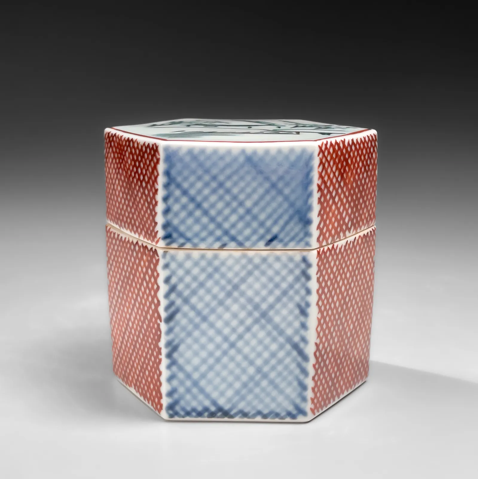 TOMIMOTO KENKICHI, Iro-e (enamel overglaze) hexagonal covered box with landscape motif of “Rain on the Yamato River”, 1960