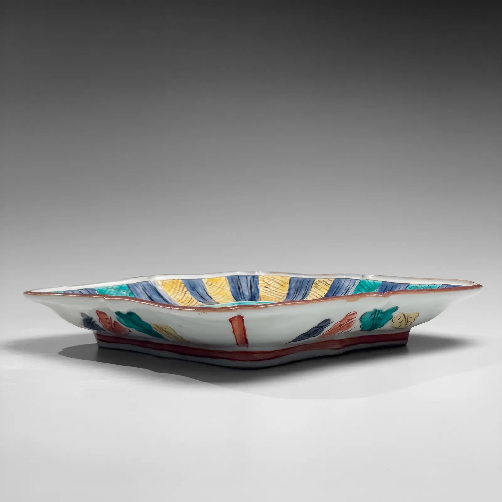 TOMIMOTO KENKICHI, Iro-e (enamel overglaze) slightly recessed rounded square platter with foliated rim, sarasatic-patterned four-petaled floral patterning, 1936