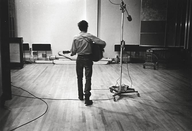 Don Hunstein, Bob Dylan, New York City [holding guitar with back to camera], August 1963