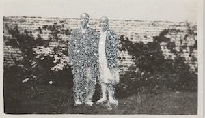 John Latour, Smiling woman holding the arm of a shoe-less man in front of a garden wall, 2020