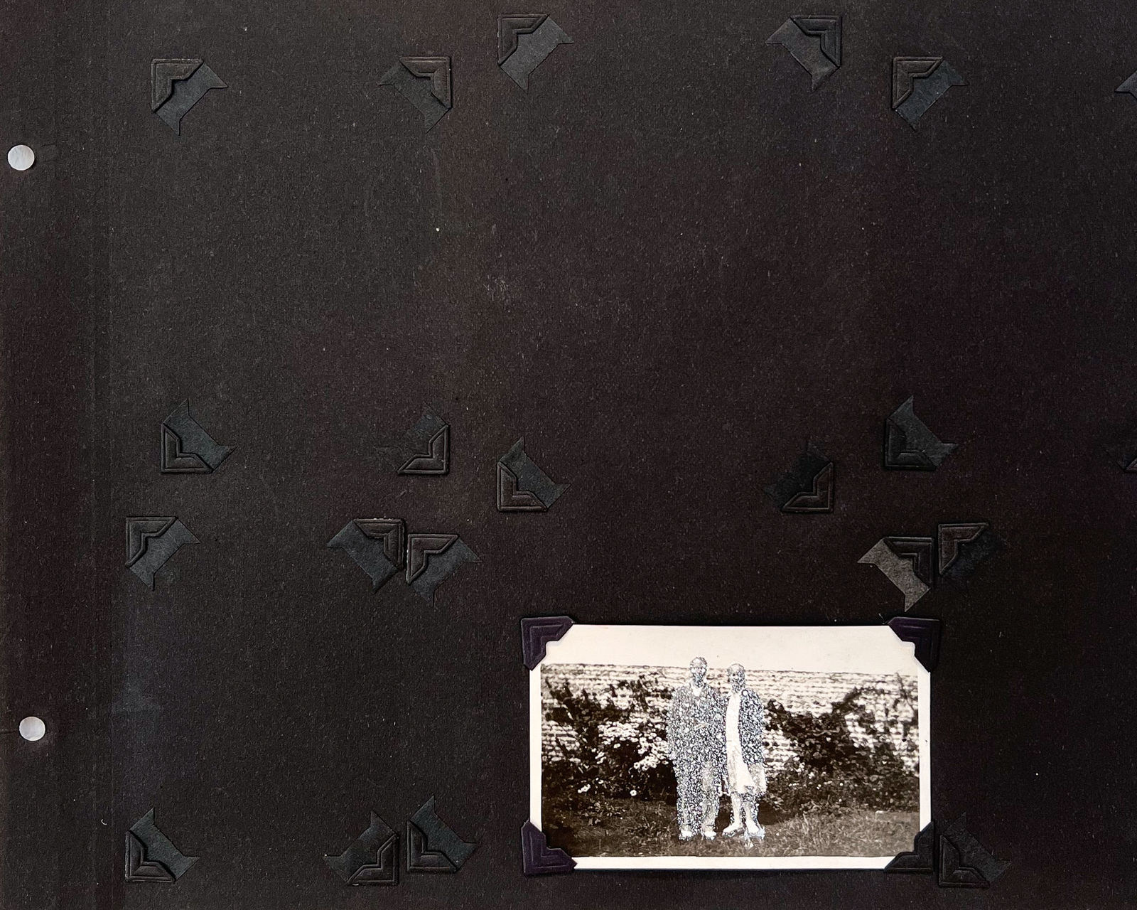 John Latour, Smiling woman holding the arm of a shoe-less man in front of a garden wall, 2020