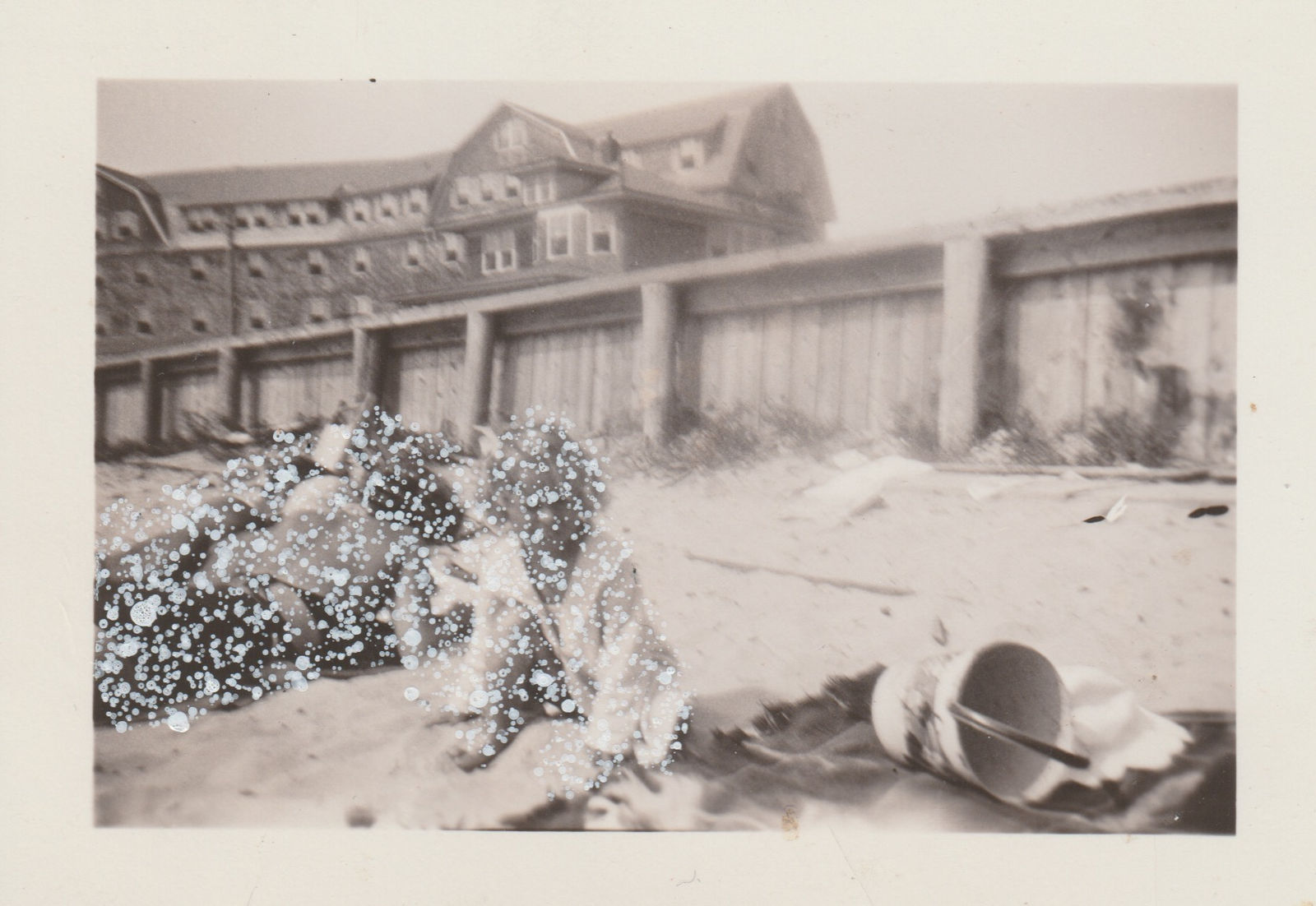 John Latour, Fair-Haired Girl Playing in the Sand while Her Parents Sunbathe Nearby, 2021
