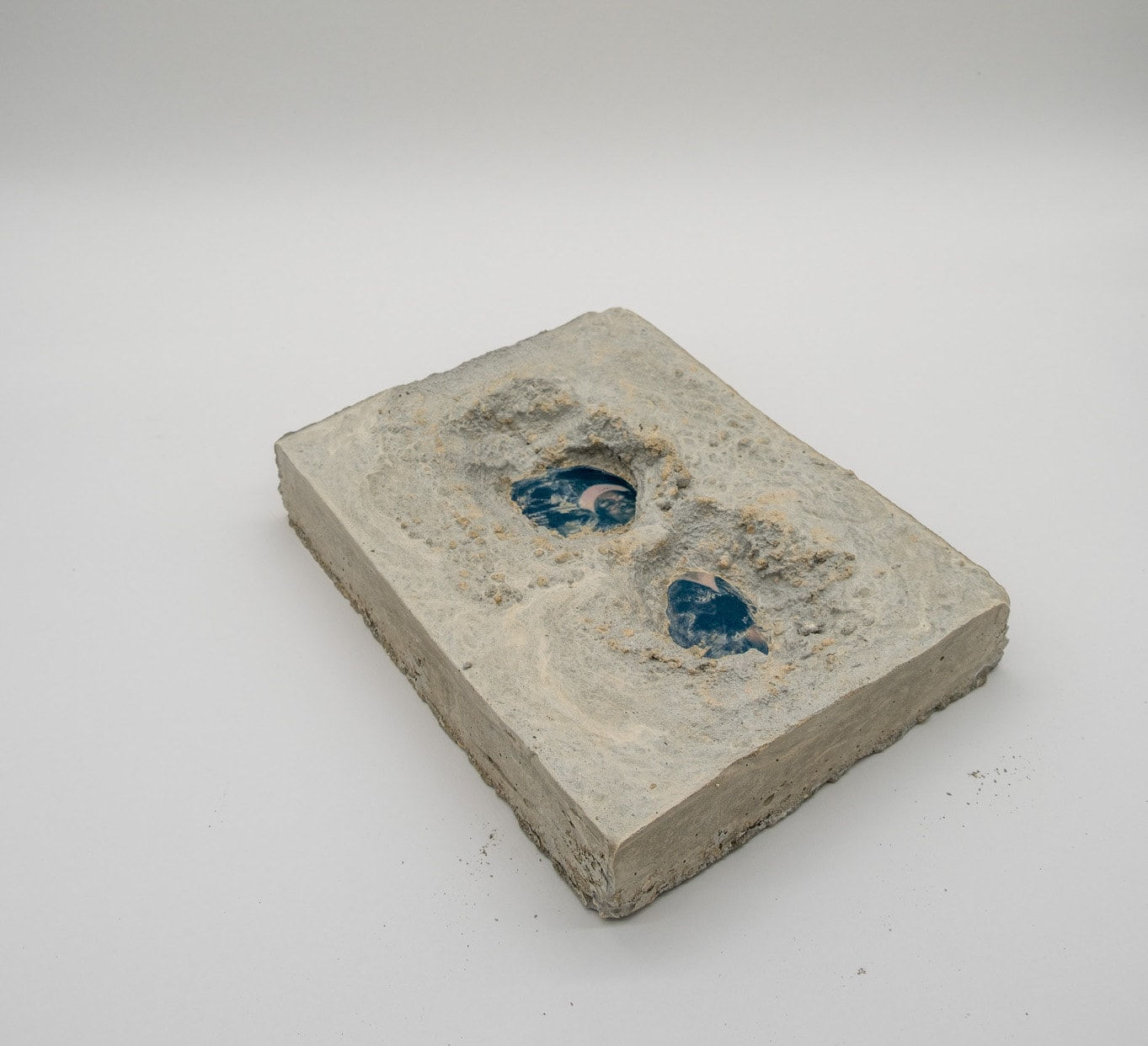 A sculpture by Shabez Jamal consisting of a photograph suspended in poured concrete that remains partially visible.