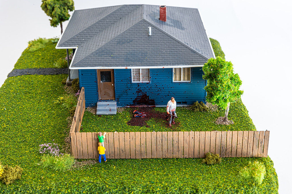 miniature diorama by Abigail Goldman of two boys looking over a fence into the yard burying dead bodies