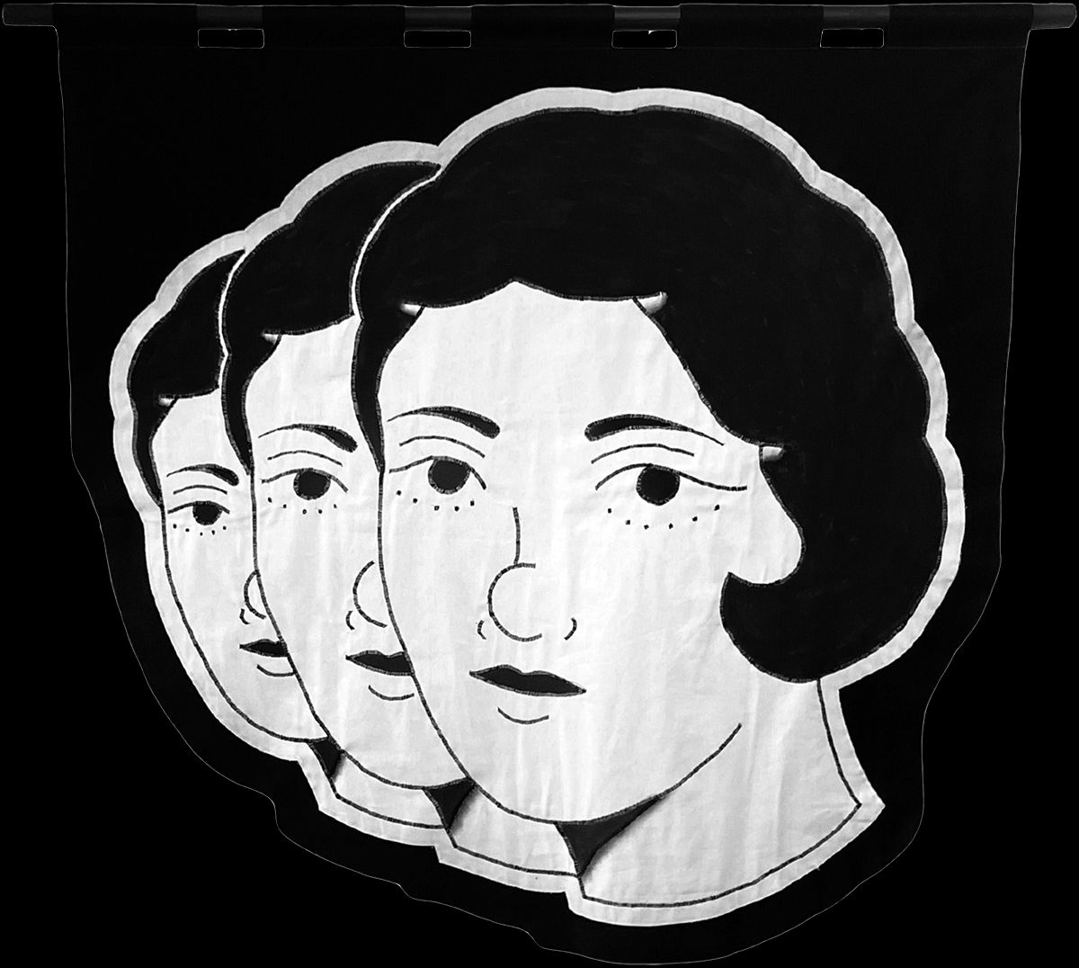 embroidered black and white banner of the heads of three woman in an angled row