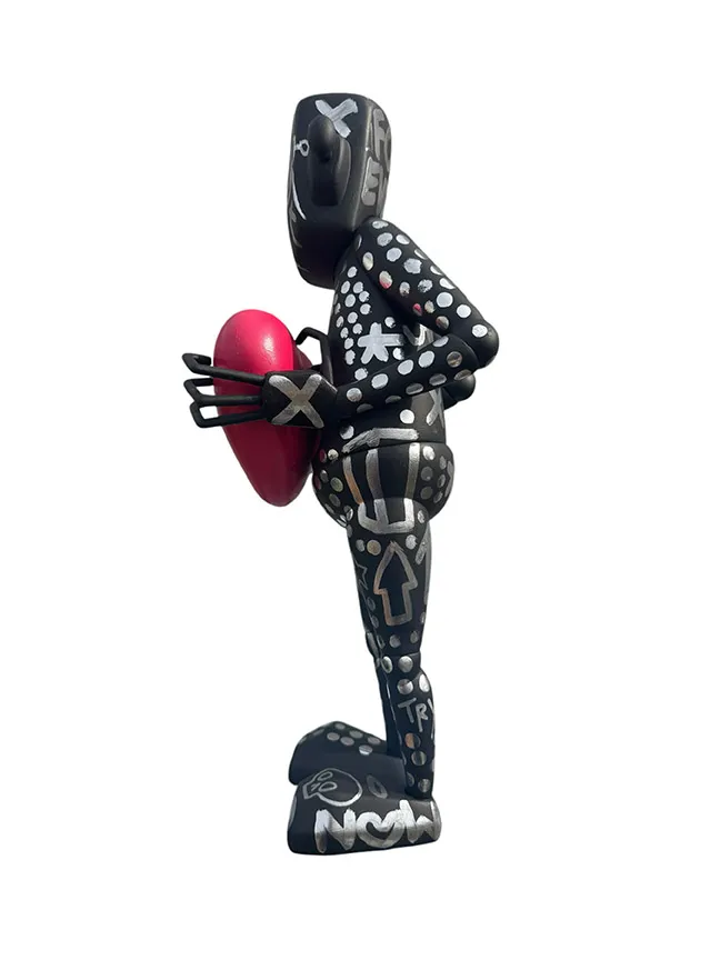 left side view of a black and silver robot statue holding a heart